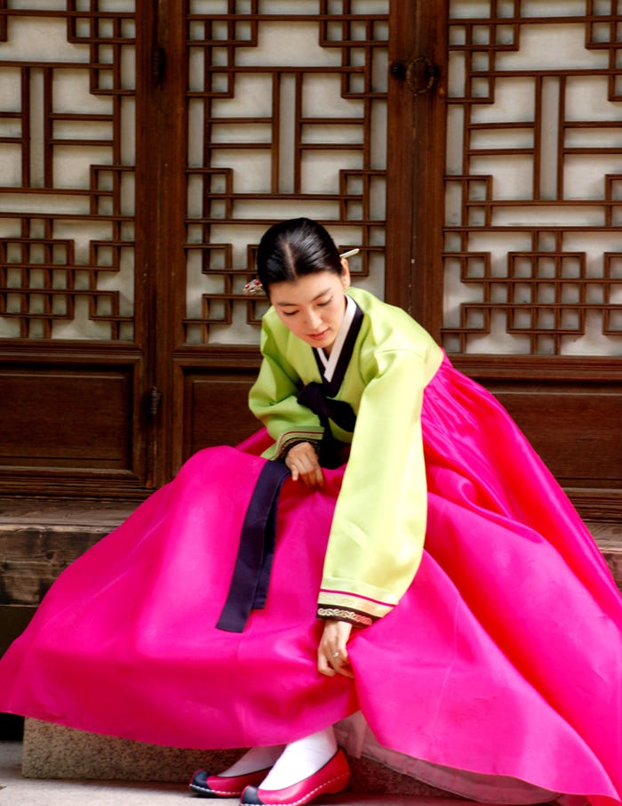 Hanbok tradicional coreano con una colorida chaqueta jeogori y una fluida falda chima que muestra las líneas elegantes y los colores vibrantes característicos de la vestimenta tradicional coreana.