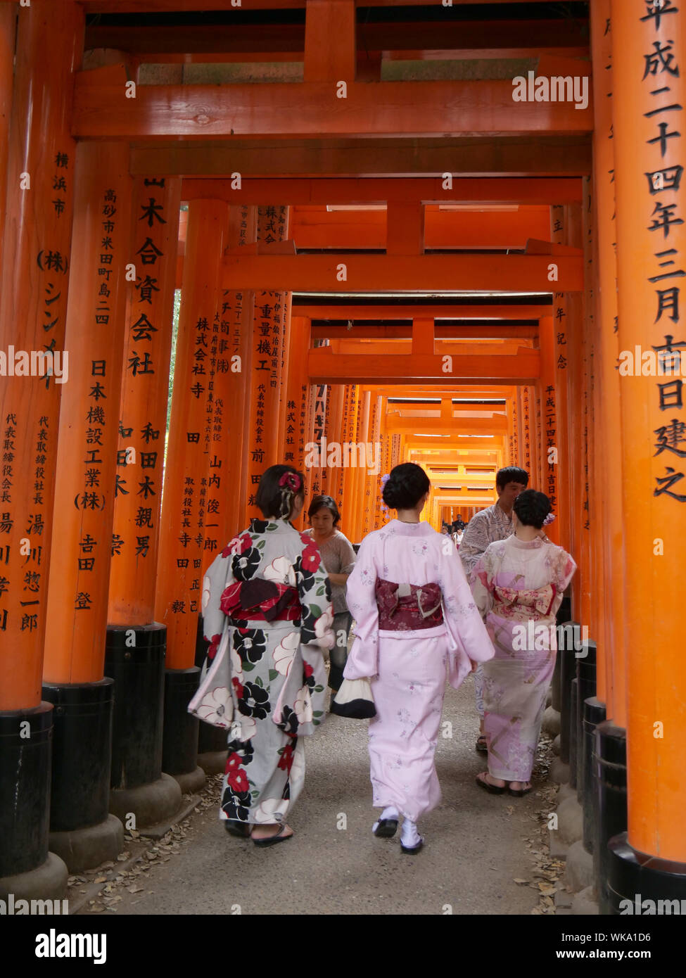 Una mujer con un kimono tradicional camina por las famosas puertas torii bermellón del santuario Fushimi Inari en Kioto, mostrando la icónica arquitectura japonesa del santuario y la fotografía cultural con kimono.