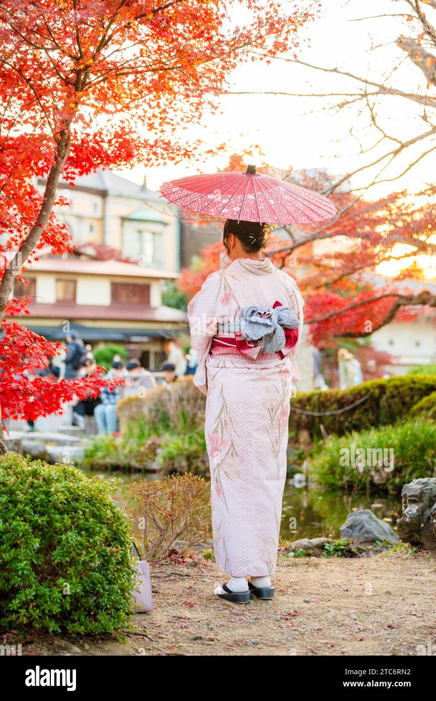 Fotografía de retrato de kimono japonés desde atrás en Kioto, Japón, con un impresionante fondo de follaje otoñal y hojas de arce que se vuelven rojas en la temporada de otoño, un ejemplo perfecto de fotografía de kimono estacional.