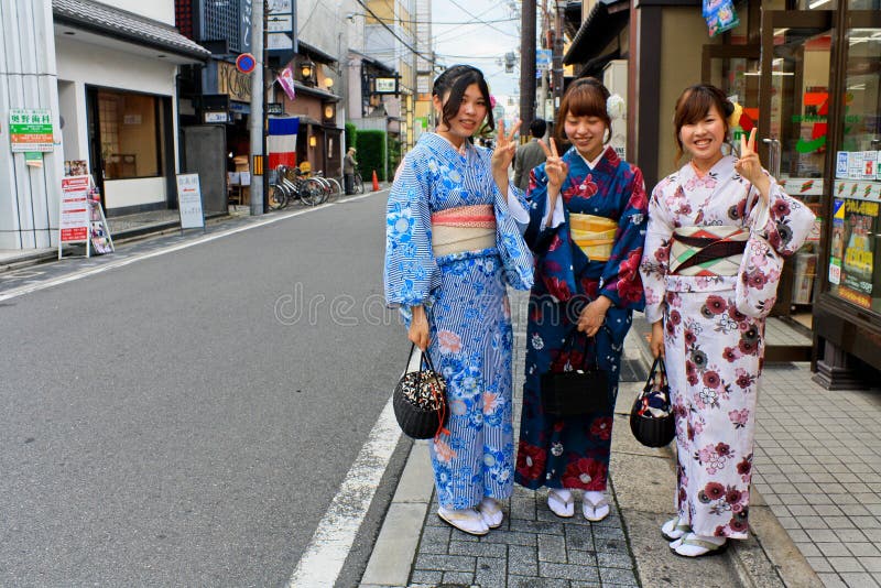 Tres mujeres respetuosas con kimonos tradicionales sonríen con gracia en el distrito de Gion, demostrando una etiqueta cultural adecuada y un comportamiento digno.