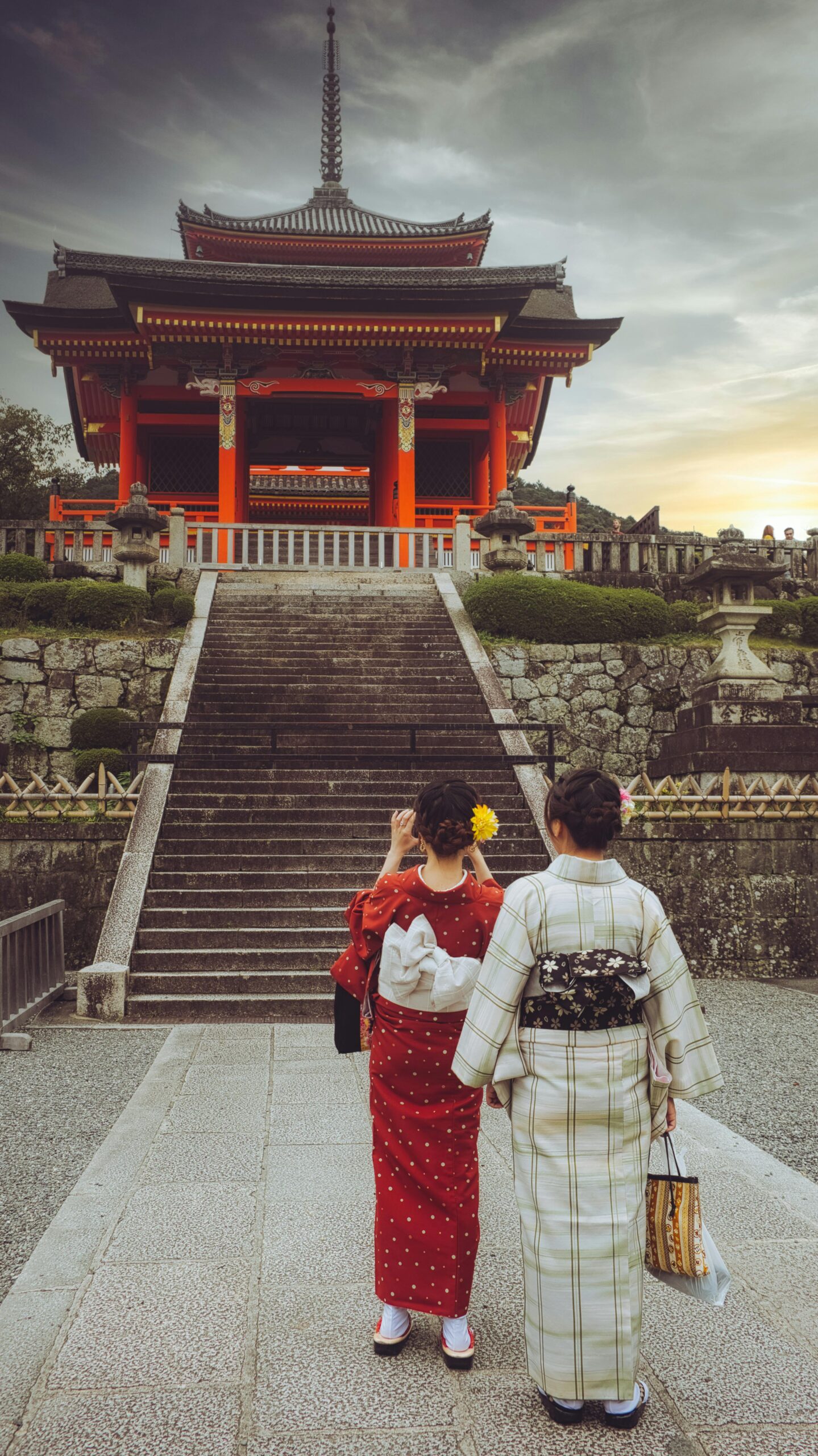 Mujeres con elegantes kimonos rojos y blancos frente a un templo japonés tradicional, demostrando una auténtica conexión cultural en Kioto.
