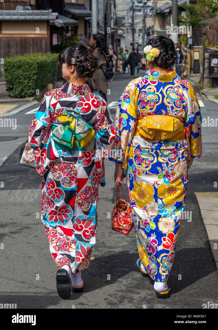 Dos elegantes mujeres con kimono tradicional caminan por las calles del histórico distrito de Gion en Kioto, mostrando la mágica transformación de turista a modelo.