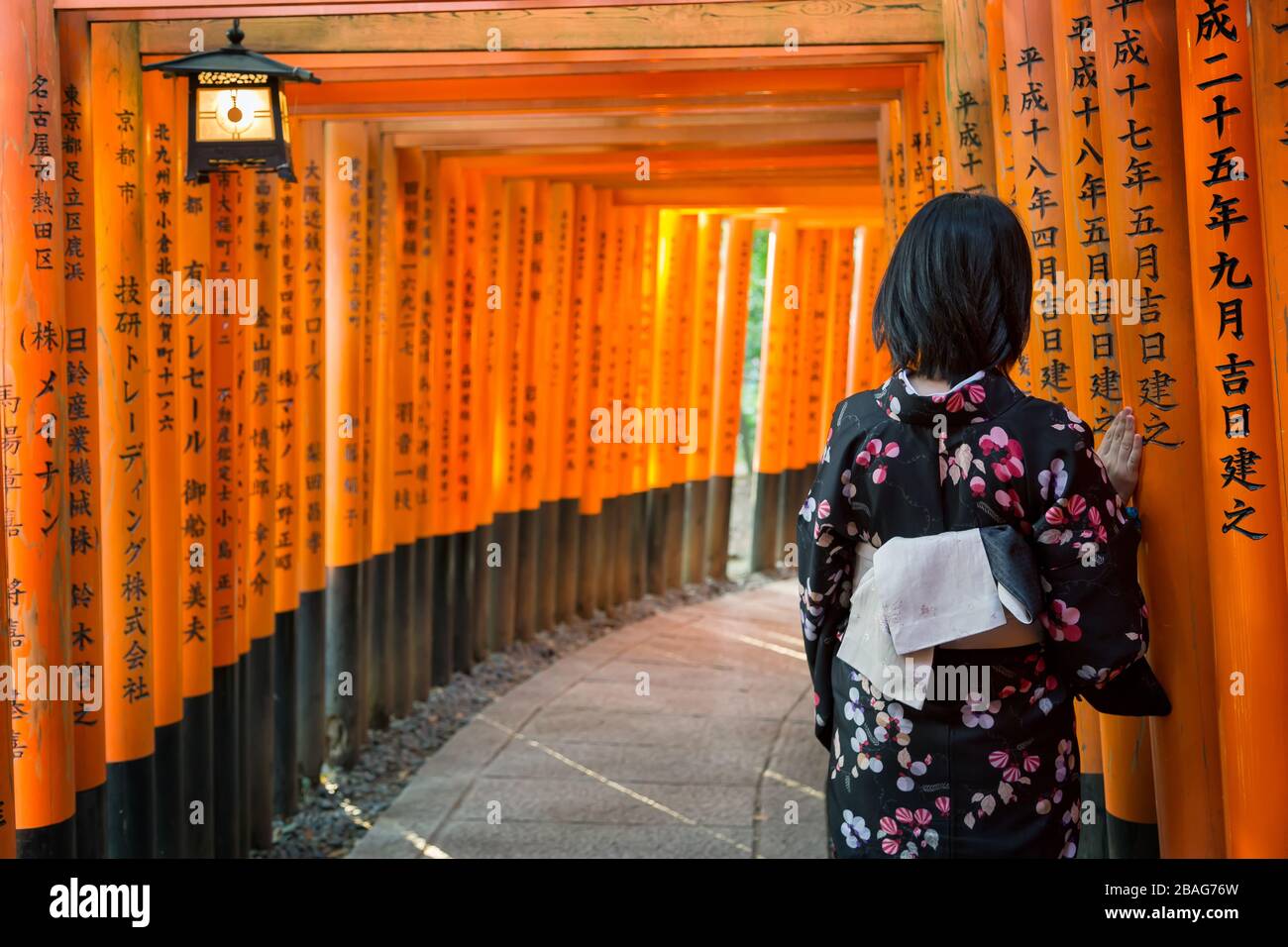 Dos mujeres con kimonos tradicionales de pie ante las icónicas puertas torii rojas del santuario Fushimi Inari en Kioto, Japón: un ejemplo perfecto de fotografía con kimonos en templos sagrados.