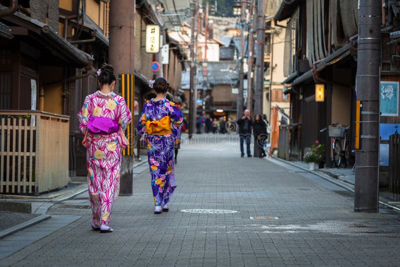 Mujeres jóvenes con vibrantes kimonos tradicionales caminando con gracia por el histórico distrito de Gion, demostrando la elegante transformación